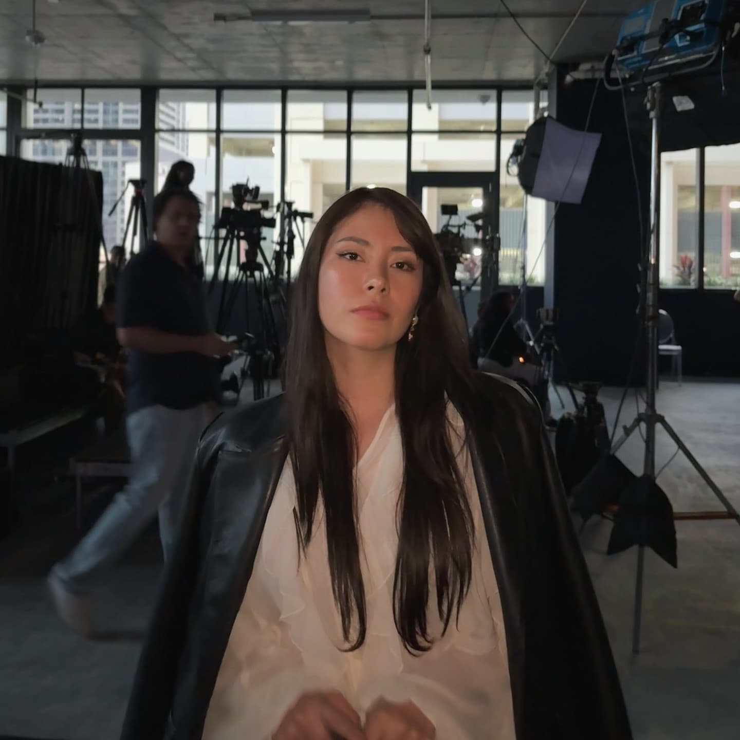 Lu on a production set with cameras and lighting behind her